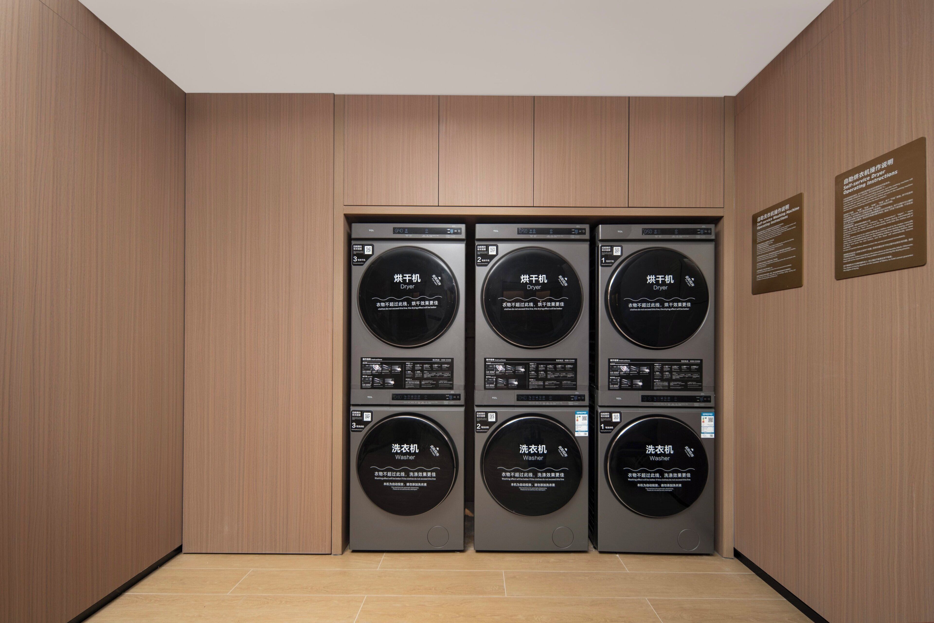 A laundry facility with four washing machines and two dryers, all in a modern, wooden-finished room.