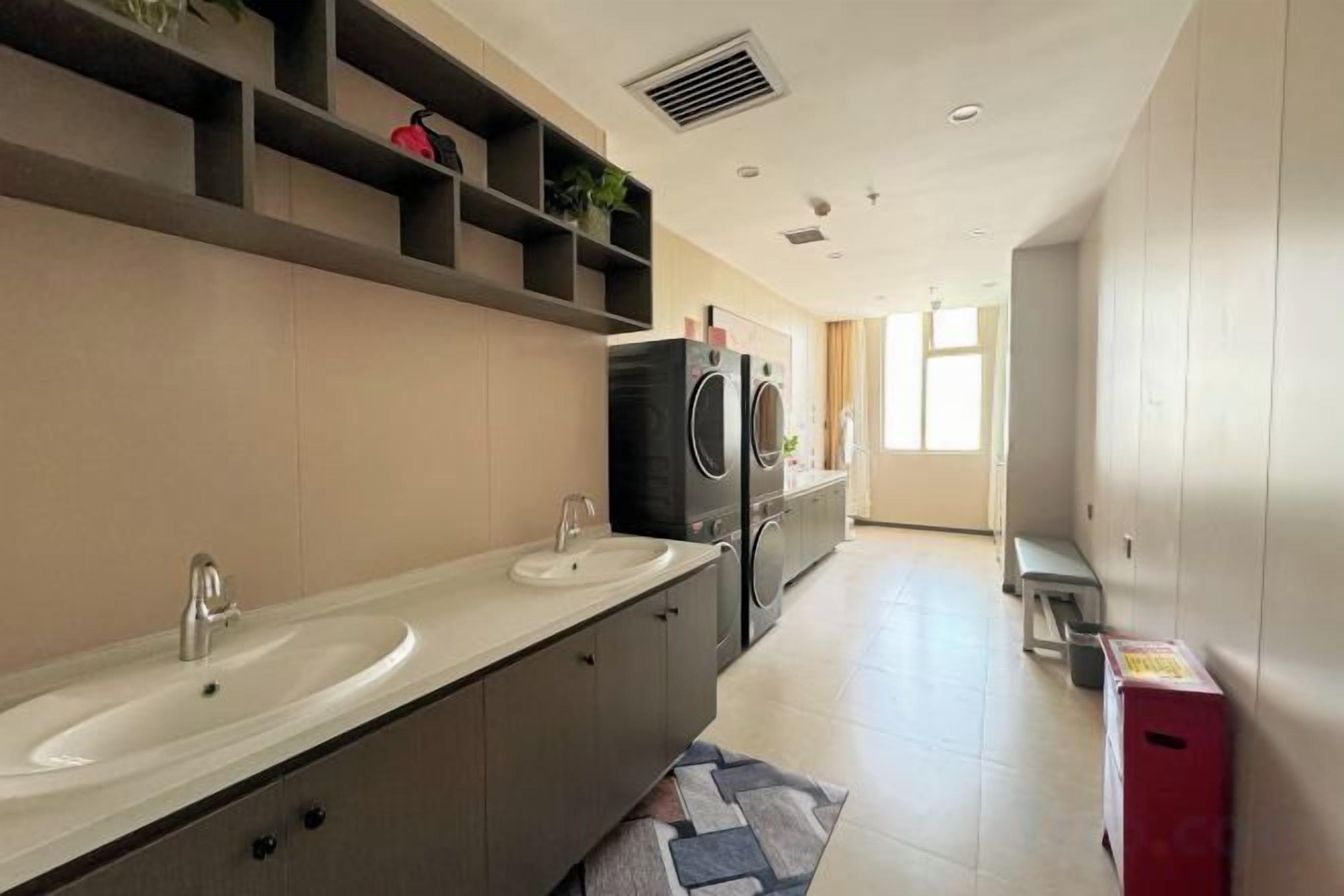 Une salle de bain moderne dotée d’un grand lavabo, d’un miroir et d’un lave-linge encastré.