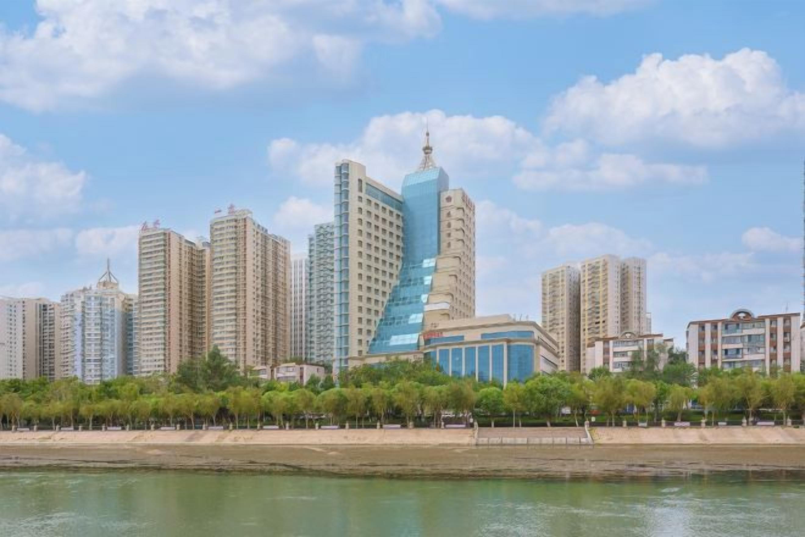 A city skyline with high-rise buildings, a waterfront, and a park with trees.