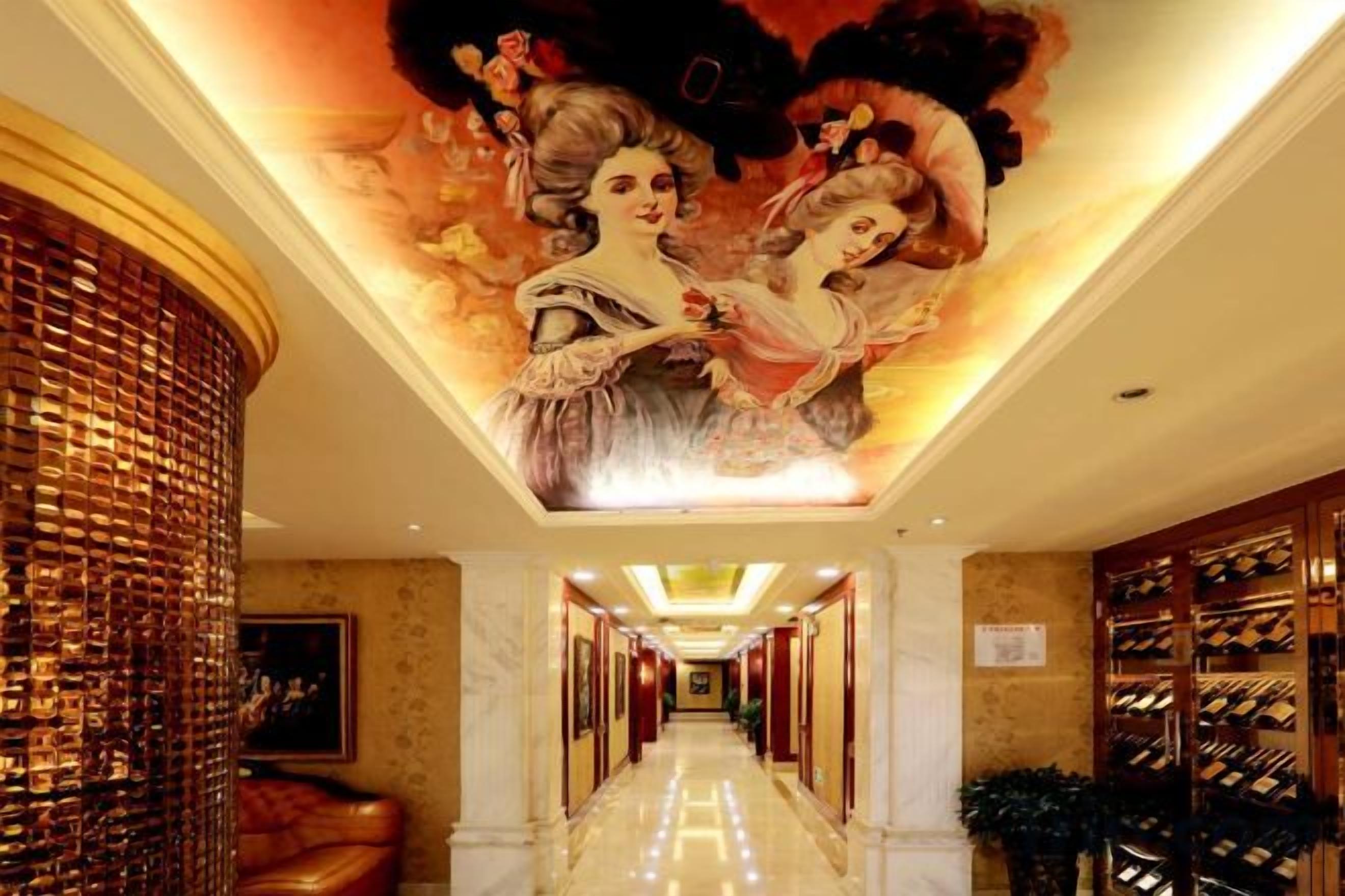 A hotel corridor with a mural, a wine rack, and a plush red sofa.
