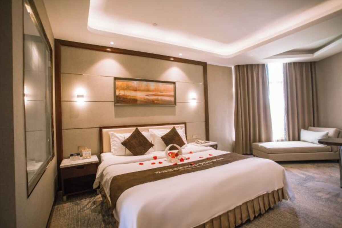 Una habitación de hotel con una cama grande, una mesita de noche, una silla y un escritorio.