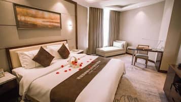 A hotel room with a large bed, a desk, a chair, and a view of the outdoors.
