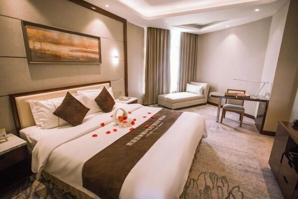 A hotel room with a large bed, a desk, a chair, and a view of the outdoors. - Korla Pear City Garden Hotel (Korla)