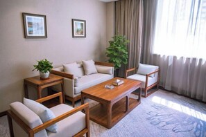 A living room with a sofa, two armchairs, a coffee table, and a potted plant. - Korla Pear City Garden Hotel (Korla)
