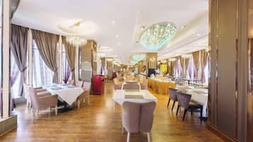 A hotel dining area with multiple tables and chairs, a bar, and a reception desk.