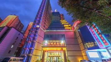 A multi-story building with a prominent entrance, large windows, and a sign indicating it is a hotel.