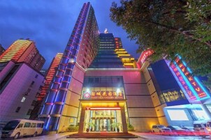 A multi-story building with a prominent entrance, large windows, and a sign indicating it is a hotel.