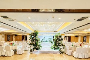 A banquet hall with round tables, white chairs, and a floral aisle. - Korla Pear City Garden Hotel (Korla)