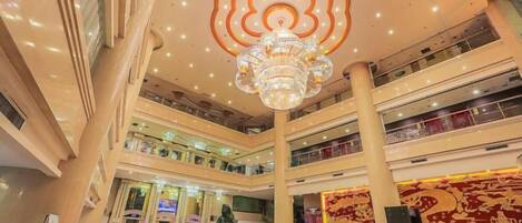 Un centro comercial de varios niveles con un atrio central, una lámpara de araña grande y una pared decorativa.