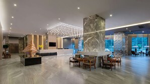Un vestíbulo amplio con mostrador de recepción, zona de estar y una escultura decorativa.