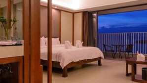 Habitación de hotel con cama, escritorio y balcón con vistas.