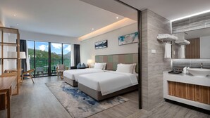 Habitación de hotel moderna con dos camas, un amplio ventanal con vistas a la montaña, un balcón, un escritorio de madera y un baño con un espejo grande y lavamanos.