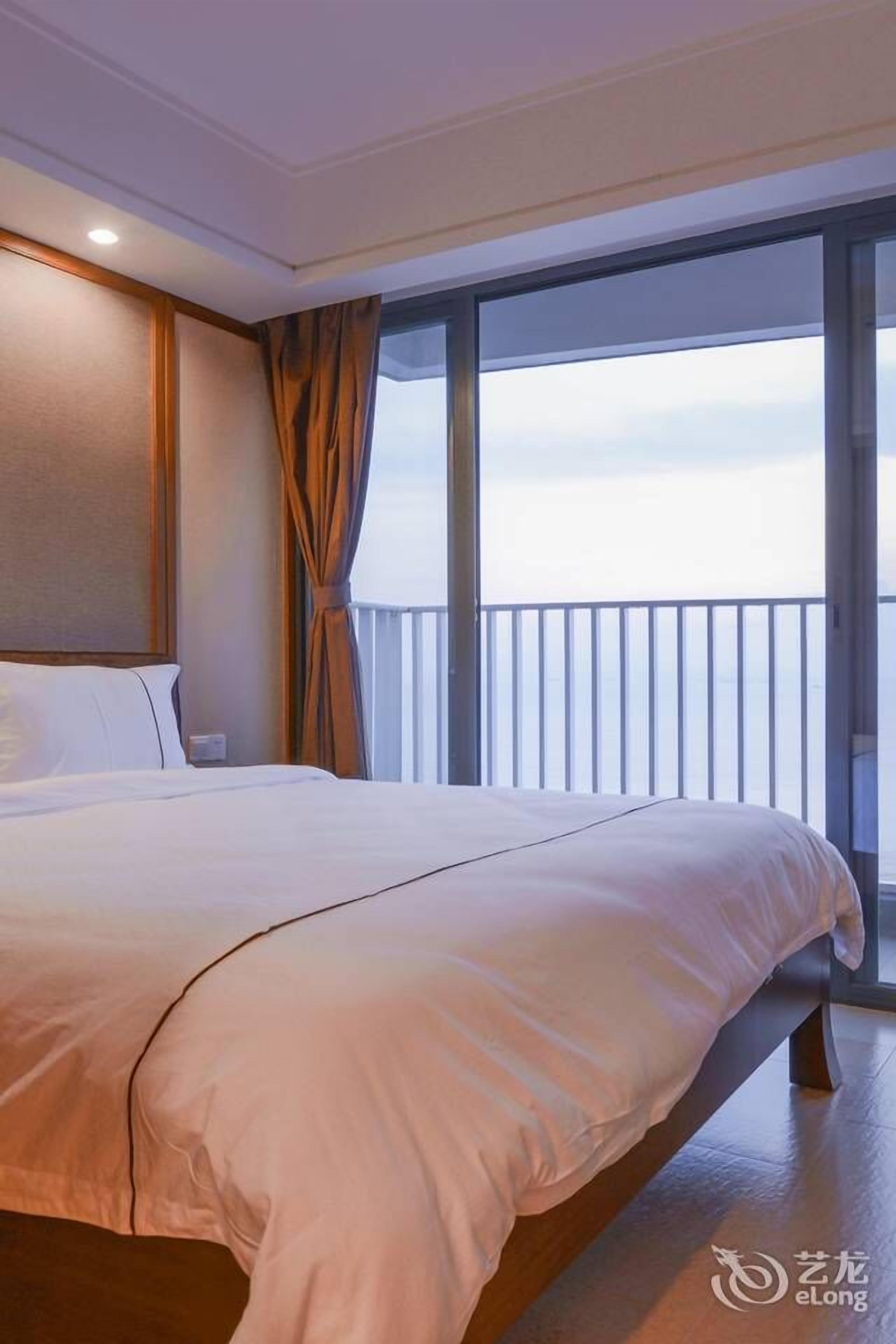 A hotel room with a large bed, a view of the sea through a balcony, and a modern interior design.