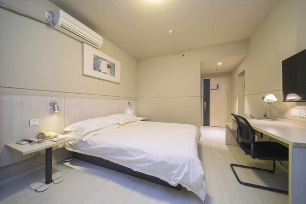 A hotel room with a bed, bedside table, desk, chair, and an air conditioning unit. - Home Inn (Changsha)