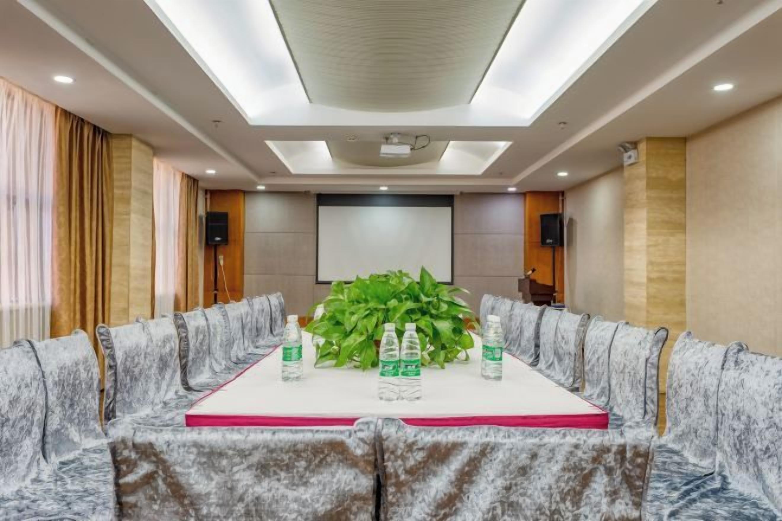 Ein Konferenzraum mit einem langen Tisch, Stühlen und einer Projektionsleinwand.