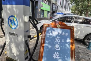 Un parquímetro con un cartel frente a un automóvil blanco.