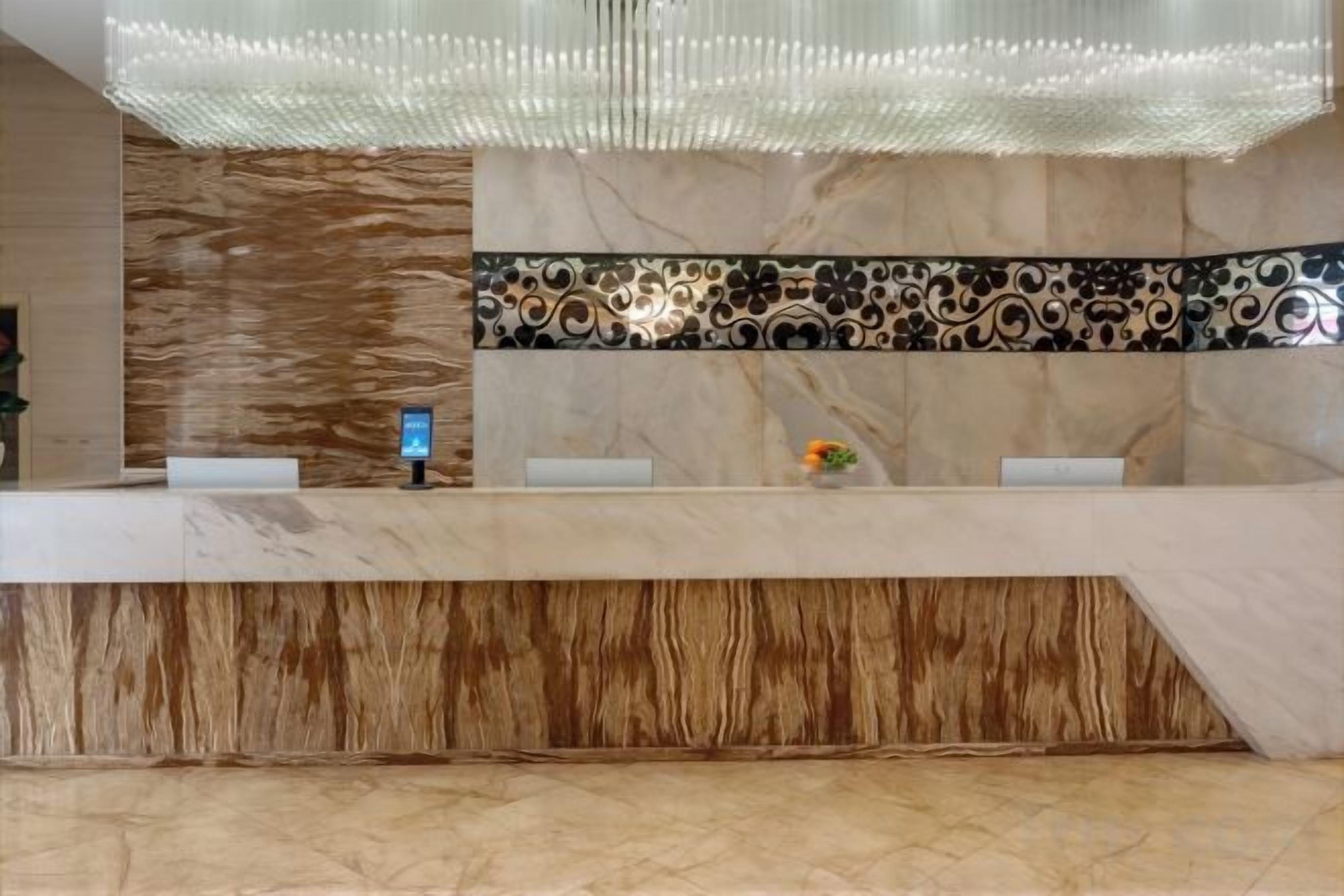 A reception desk with a modern design, a digital screen, and a decorative tile backsplash.
