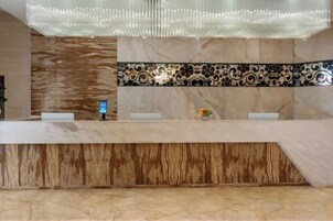 Un mostrador de recepción con diseño moderno, una pantalla digital y un elegante revestimiento de azulejos.