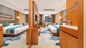 Quarto de hotel com duas camas, uma escrivaninha, uma cadeira e vista para a cidade.