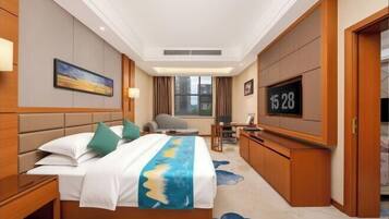 Een hotelkamer met een bed, een bureau, een televisie en uitzicht op gebouwen.