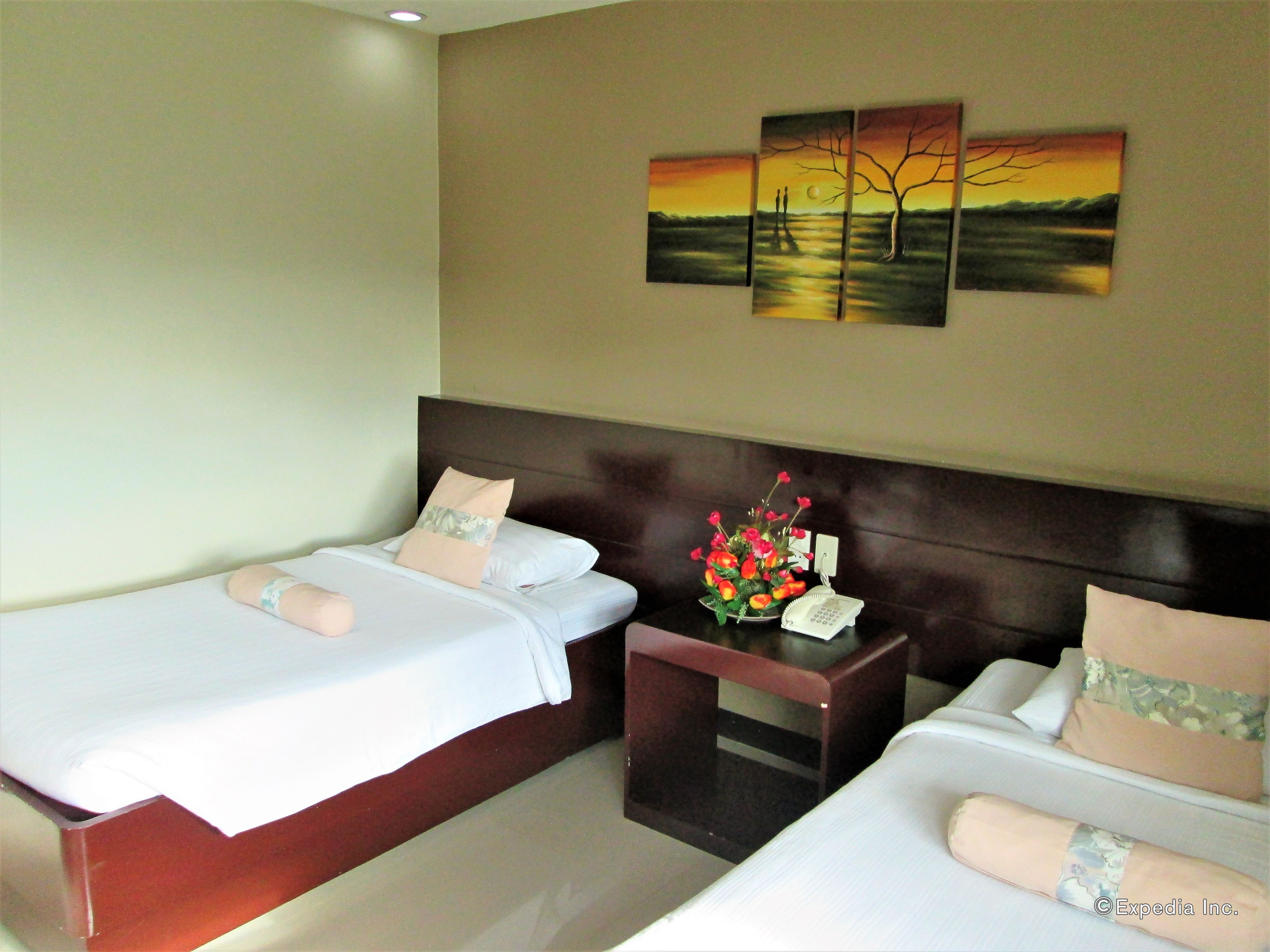 A hotel room with two beds, a nightstand with a phone, and a painting on the wall.