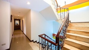 A modern staircase with a wooden handrail and metal balusters, leading to a landing with a light fixture. - Seashell Bay Hotel (Hengchun)