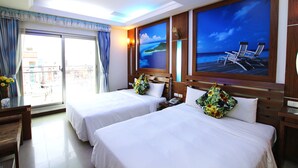 A hotel room with two beds, a balcony with a view, and a large painting of a beach scene. - Seashell Bay Hotel (Hengchun)