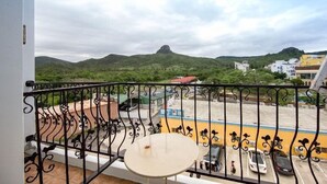 A balcony with a view of a parking lot and hills. - Seashell Bay Hotel (Hengchun)
