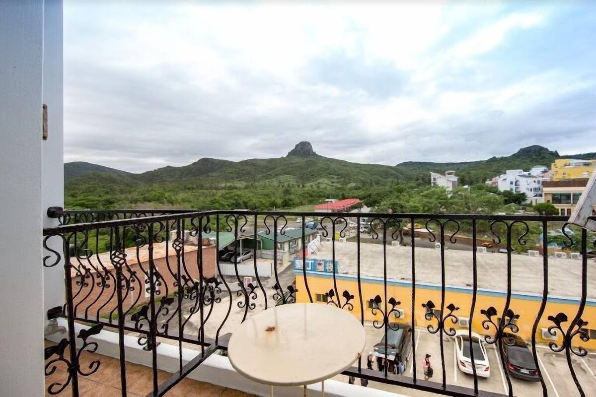 A balcony with a view of a parking lot and hills.