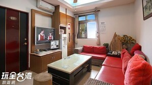 A living room with a television, sofa, and a ceiling fan. - Seashell Bay Hotel (Hengchun)