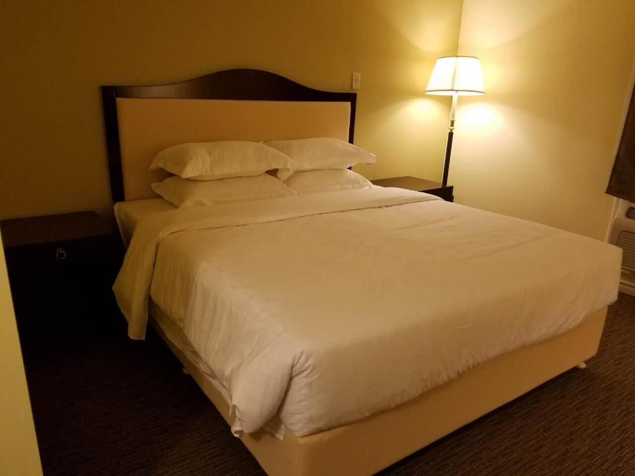 Una cama bien hecha con sábanas blancas en una habitación de hotel.