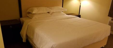 Una cama bien hecha con sábanas blancas en una habitación de hotel.