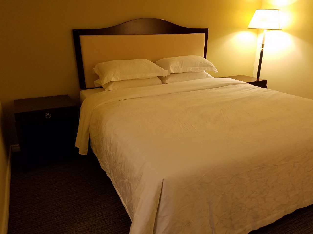 Una cama bien hecha con sábanas blancas en una habitación de hotel.