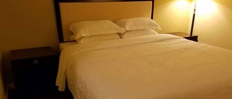 Una cama bien hecha con sábanas blancas en una habitación de hotel.