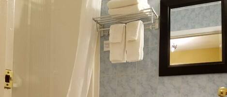 A bathroom with a shower, toilet, sink, and towel rack.