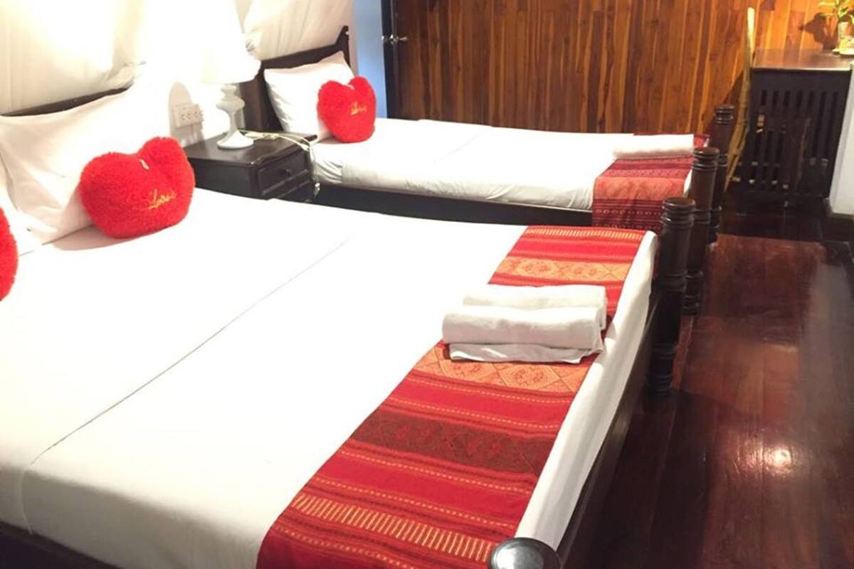 A hotel room with two beds, each with white linens and red decorative pillows.