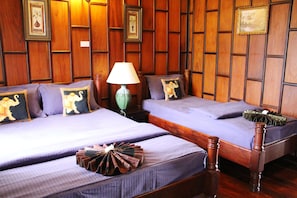 A hotel room with two beds, wooden paneling on the walls, and a green lamp on the nightstand.