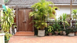 A courtyard with a wooden door, potted plants, and a tiled roof. - Villa Senesouk (Luang Prabang)