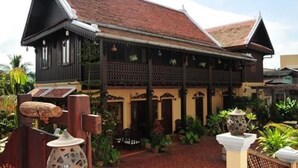 A traditional wooden house with a tiled roof, a covered porch, and a brick pathway. - Villa Senesouk (Luang Prabang)
