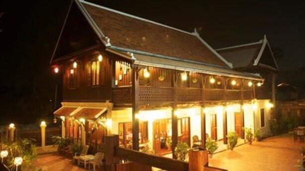 A traditional wooden building with multiple balconies and a covered patio area. - Villa Senesouk (Luang Prabang)