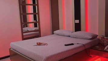 Une chambre moderne avec un lit, une table de chevet et une bande lumineuse à LED rouge le long du bord du lit.