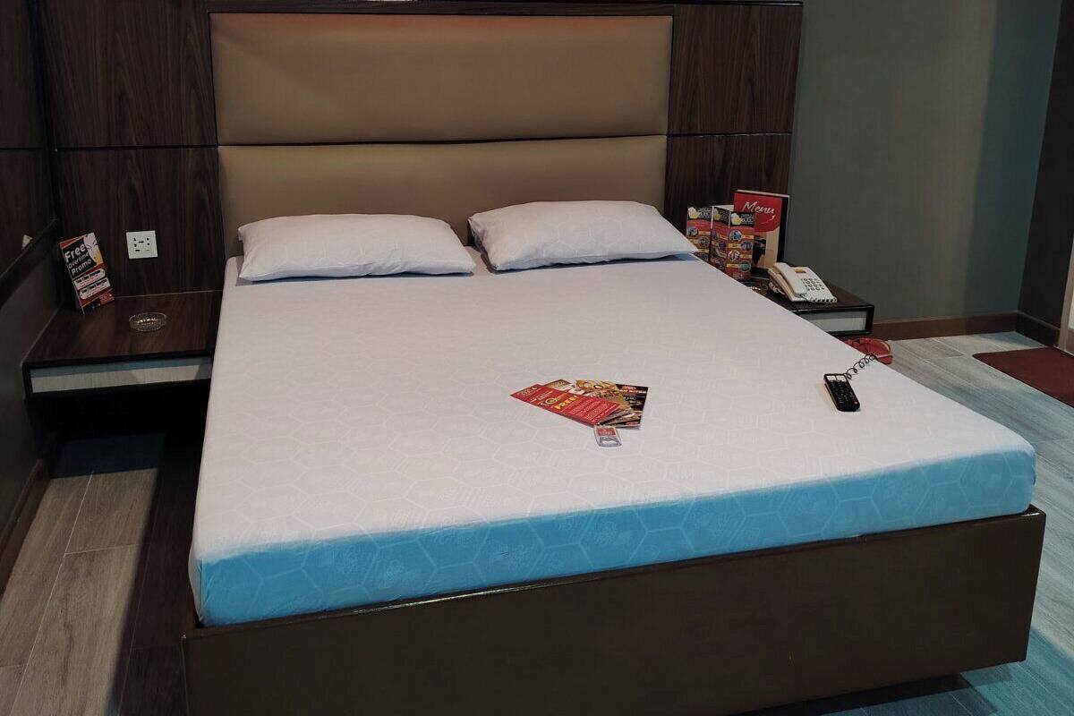 A modern hotel room with a large bed, a nightstand, a bedside table, and a wall-mounted phone.