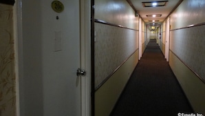 A narrow, dimly lit hallway with doors marked with numbers, suggesting a hotel or similar accommodation. - Hotel Sogo Quirino Motor Drive Inn (Manila)