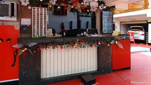 A hotel reception desk with a Christmas decoration, a menu board, and a parking garage in the background. - Hotel Sogo Quirino Motor Drive Inn (Manila)