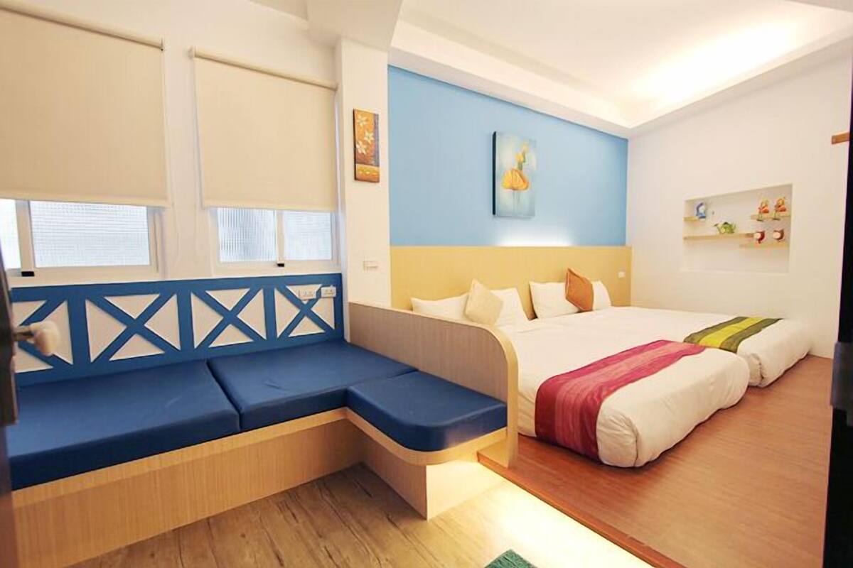 A room with a bed, a blue sofa, and a painting on the wall.