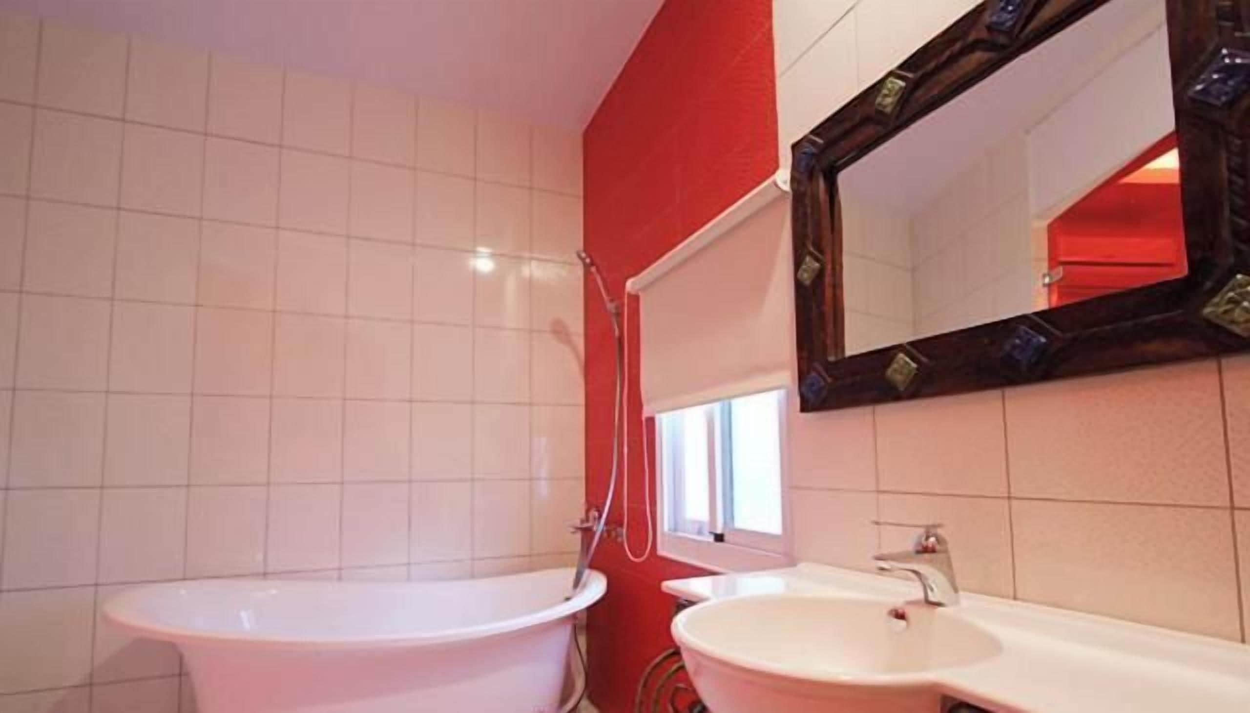 A bathroom with a bathtub, a sink, and a mirror.