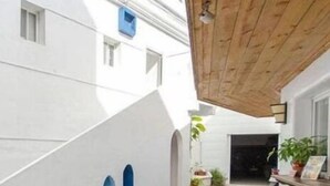 A building with a white exterior, a wooden ceiling, and a small arched window. - Kenting Hostel (Hengchun)