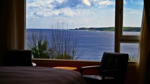 Una habitación con un amplio ventanal que da a una masa de agua y una tierra distante.