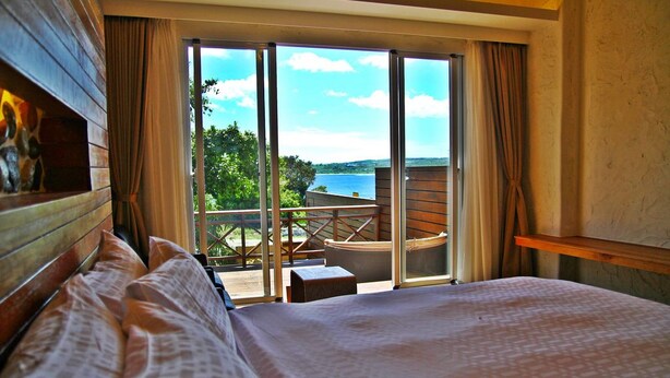 Un dormitorio con una cama grande, cabecera de madera y vistas a un balcón con mesa y sillas.