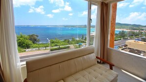 Una habitación con un ventanal grande que ofrece vista al océano y una playa distante.